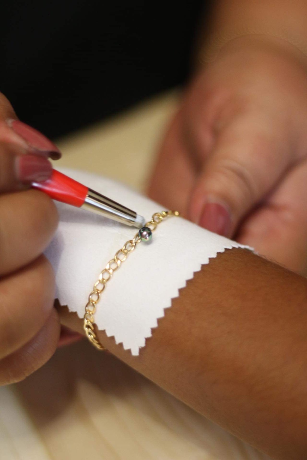 Detail of a pearl charm on a gold bracelet